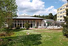 Das Caféhaus und der Pavillon Haus Waldeck mit grüner Wiese davor.